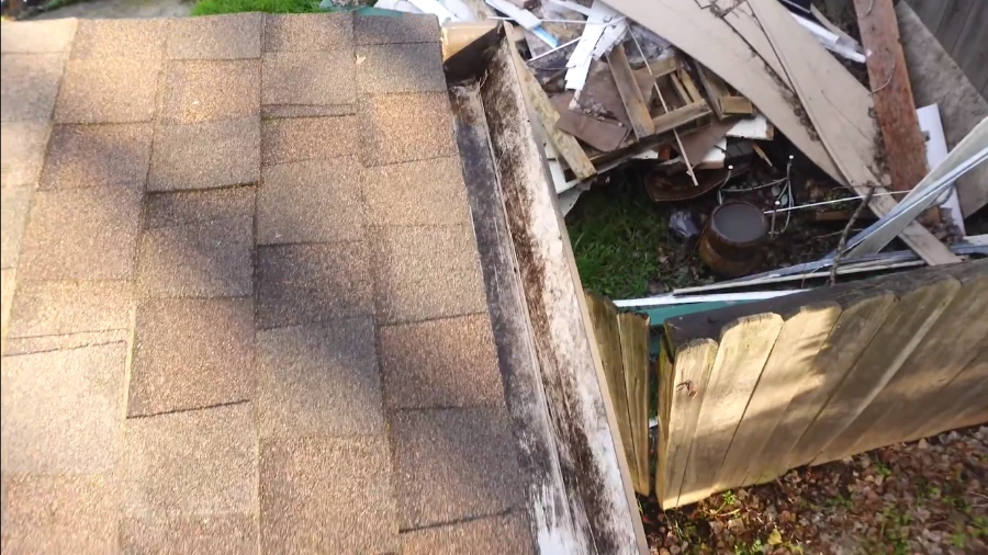 Emptied gutter with black mildew stains inside, the line that shows where water sat after the rain